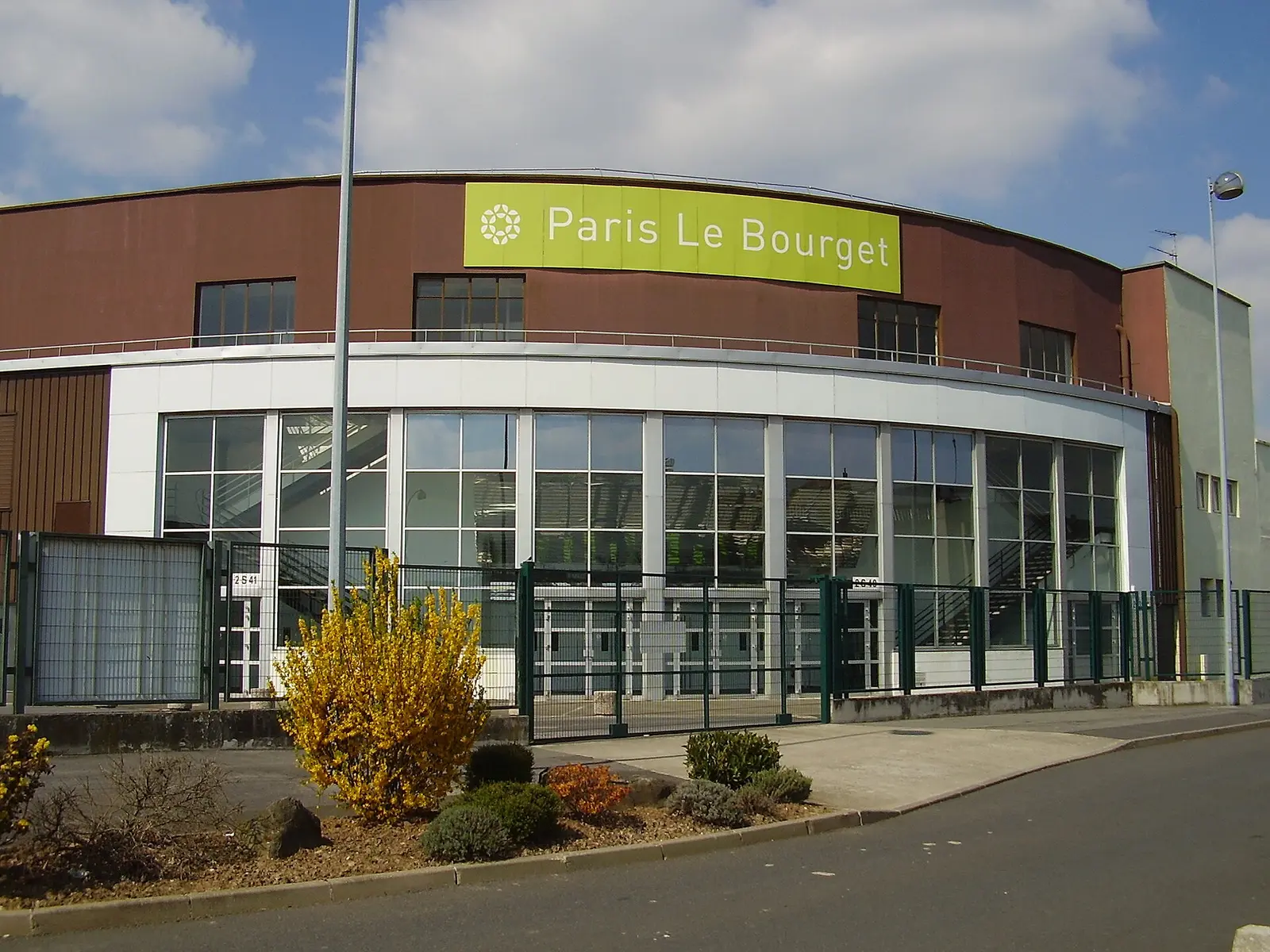 Curved entrance building of the Paris Le Bourget exhibition centre with its green sign
