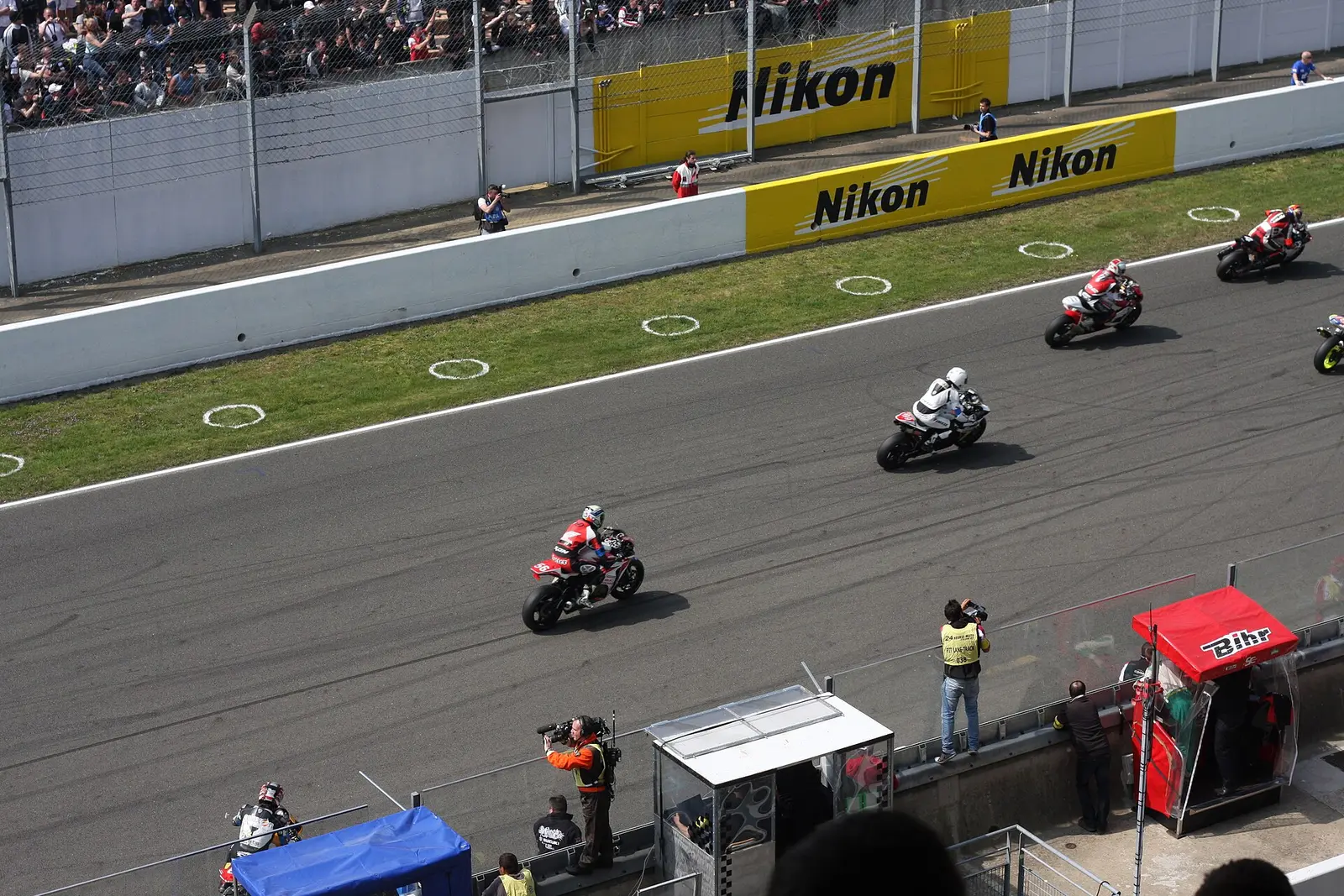 Motorcycles racing past the pit wall at the 24 Heures Motos at the Bugatti circuit in Le Mans