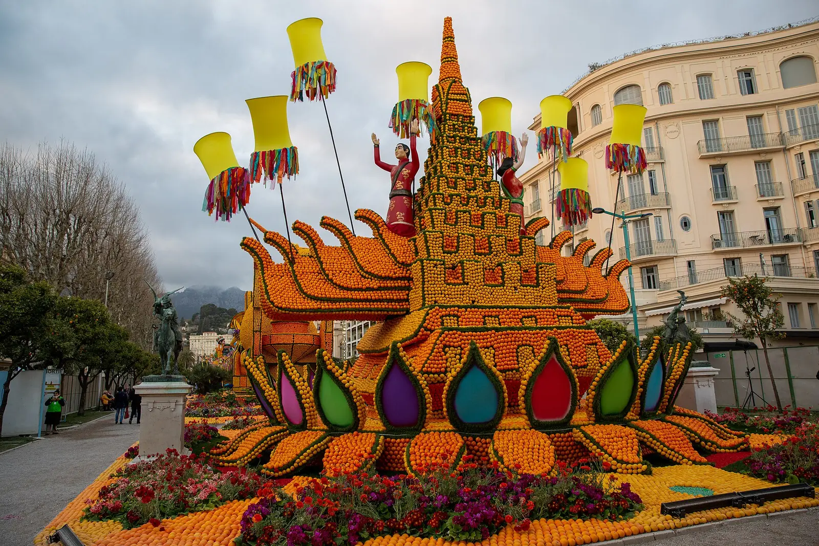 Large sculpture covered in lemons and oranges in a Menton garden with seafront buildings behind