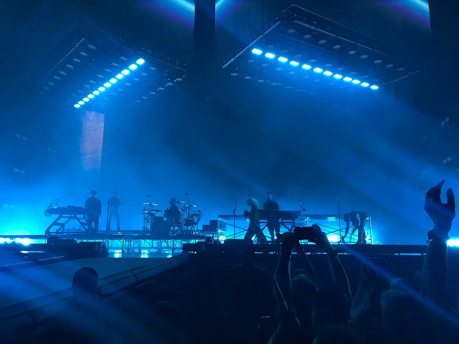 Band on a lit stage seen from the crowd inside the Paris La Défense Arena in Nanterre