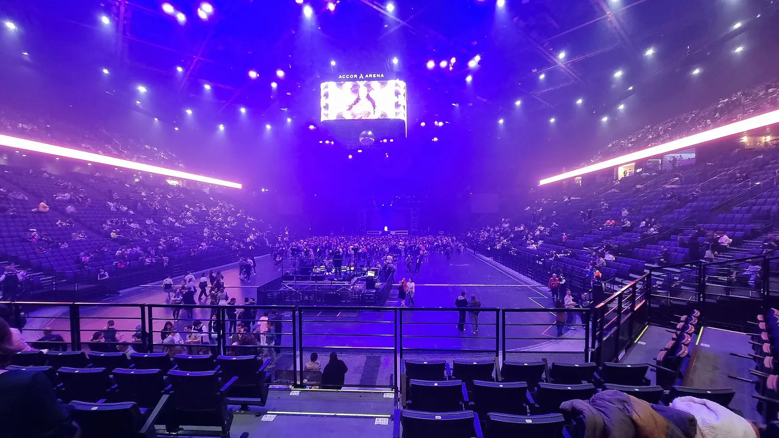 Inside the Accor Arena in Paris with purple stage lighting over the floor and tiered seating