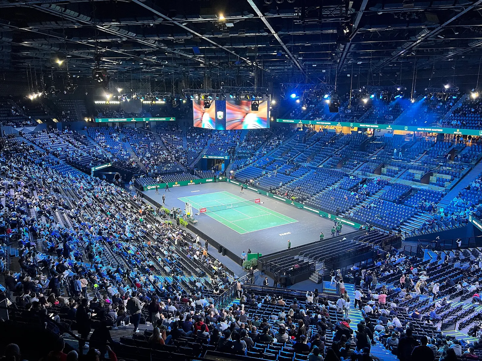Indoor tennis arena in Paris with a crowd watching a match on a hard court during the Paris Masters